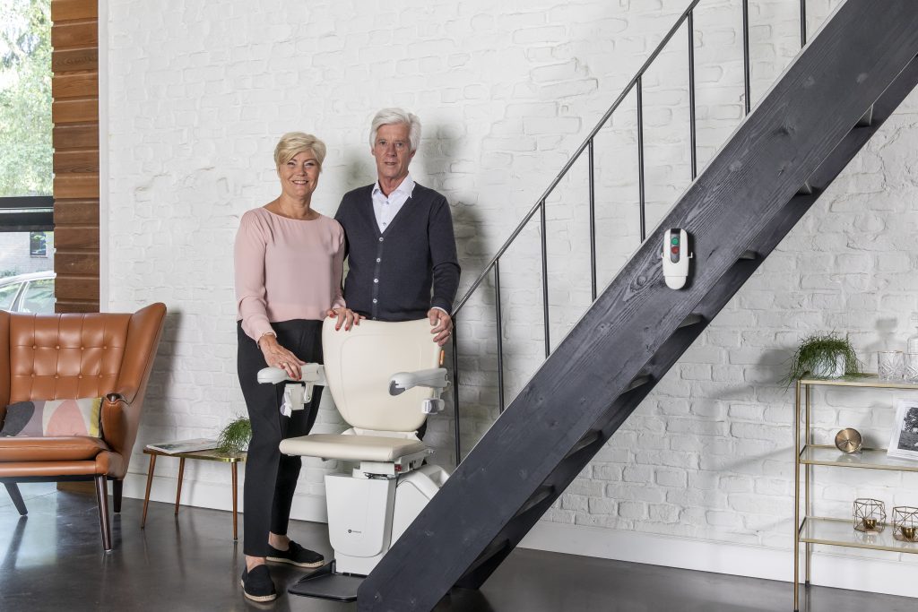 Couple posing with the stairlift of their choice 1100 Stairlift